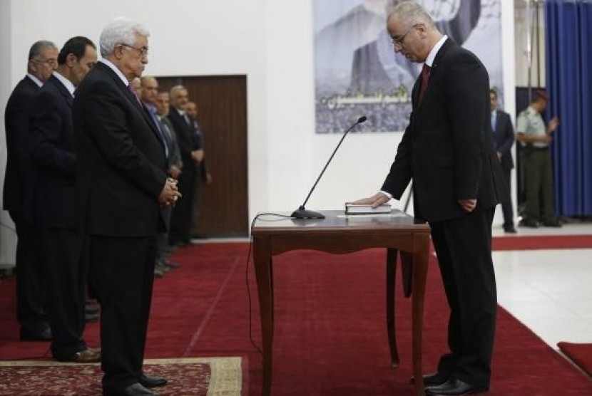 Palestinian Prime Minister Rami Hamdallah (right) stands in front of Palestinian President Mahmoud Abbas during a swearing-in ceremony of the unity government, in the West Bank city of Ramallah June 2, 2014.