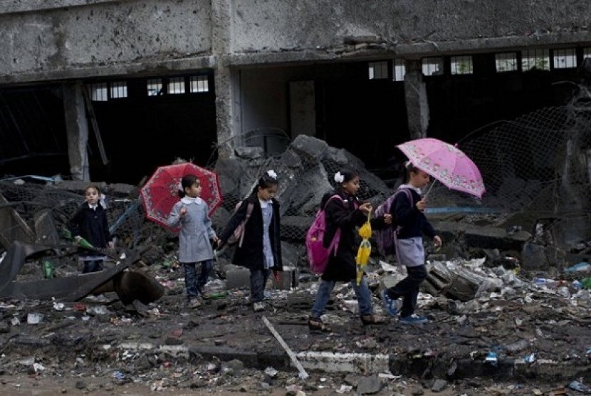 Palestinian schoolchildren walk in debris by a damaged school in Gaza City, Saturday, Nov. 24, 2012. Schools in Gaza opened Saturday for the first time since the truce.  