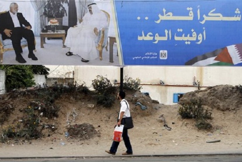 Palestinian youth walks near a poster of Gaza's Hamas Prime Minister Ismail Haniyeh (left) and Emir of Qatar Sheikh Hamad bin Khalifa al-Thani in Gaza City, Sunday, Oct. 21, 2012. The poster announces the coming visit of the Emir of Qatar, it reads, 