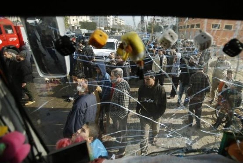 Palestinians are pictured through the damaged windscreen of a bus as they gather at the scene of an Israeli air strike, which hit a motorcycle, in the northern Gaza Strip January 19, 2014.