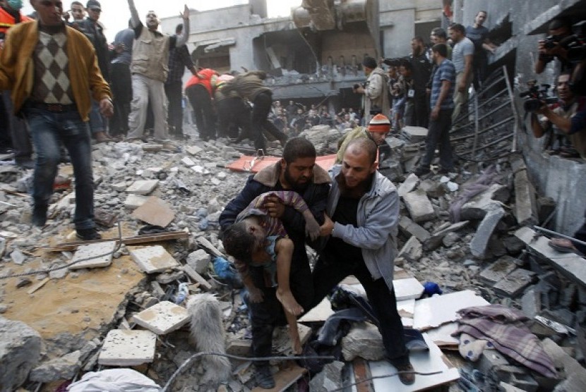  Palestinians carry the dead body of a child from under the rubble of a house after an Israeli air strike in Gaza City November 18, 2012. 