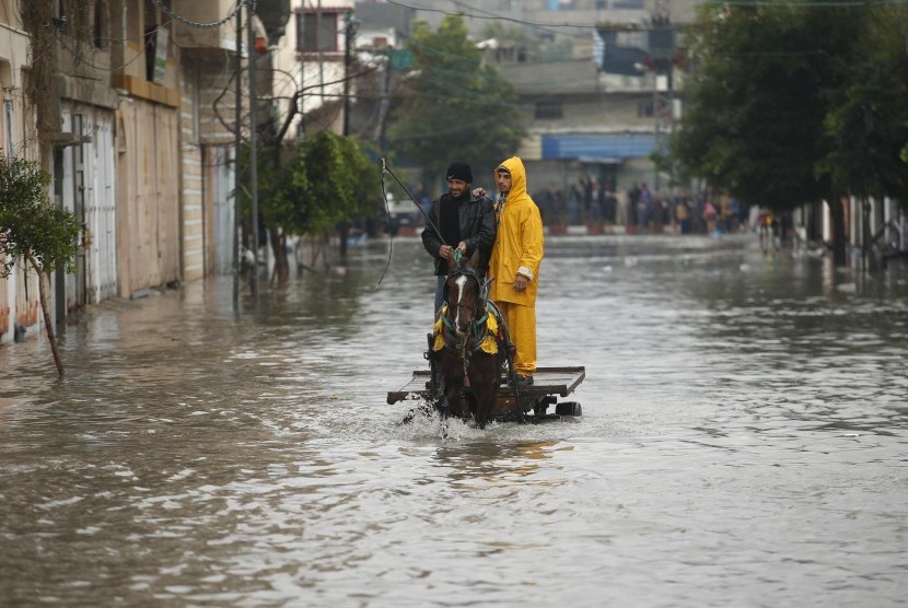 Palestinians ride a horse cart through a flooded road following heavy rain in Gaza City November 27, 2014. The civil defence asked residents in an area east of Gaza City to evacuate their homes to avoid being trapped in flood waters from a nearby lake.