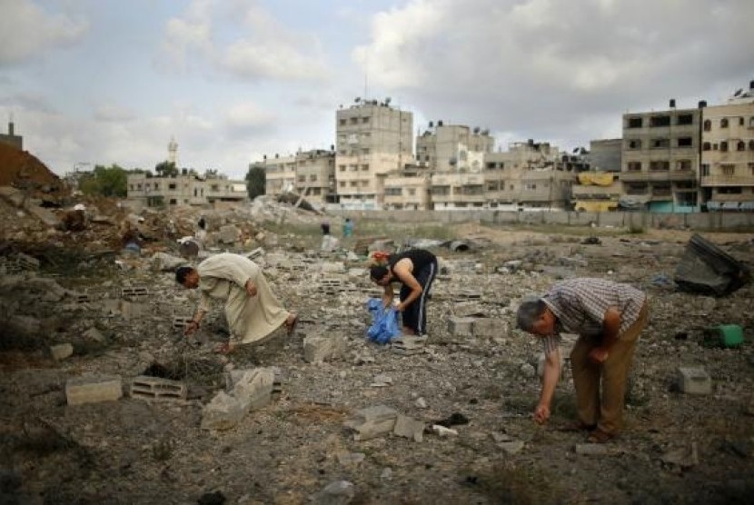 Palestinians search for scattered body parts amongst the rubble of Tayseer Al-Batsh's family house, which police said was destroyed in an Israeli air strike in Gaza City July 13, 2014.