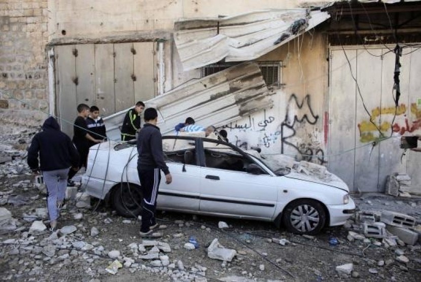 Palestinians stand next to a car damaged during the demolition of Abdel-Rahman Shaloudi's home in the East Jerusalem neighborhood of Silwan November 19, 2014.