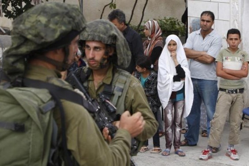 Palestinians stand outside their house as Israeli soldiers take part in an operation to locate three Israeli teens near the West Bank City of Hebron June 21, 2014.
