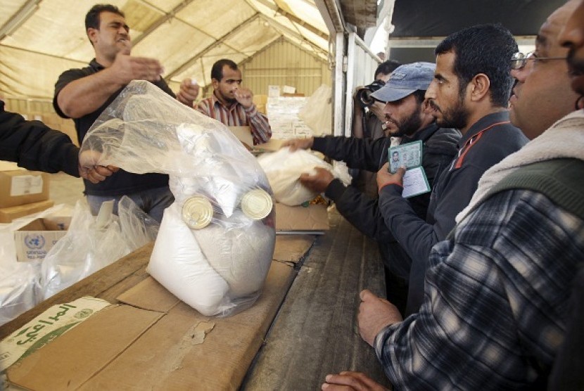 Palestinians wait to receive food supplies from the United Nations Relief and Works Agency (UNRWA) headquarters in Rafah in the southern Gaza Strip November 20, 2012.   