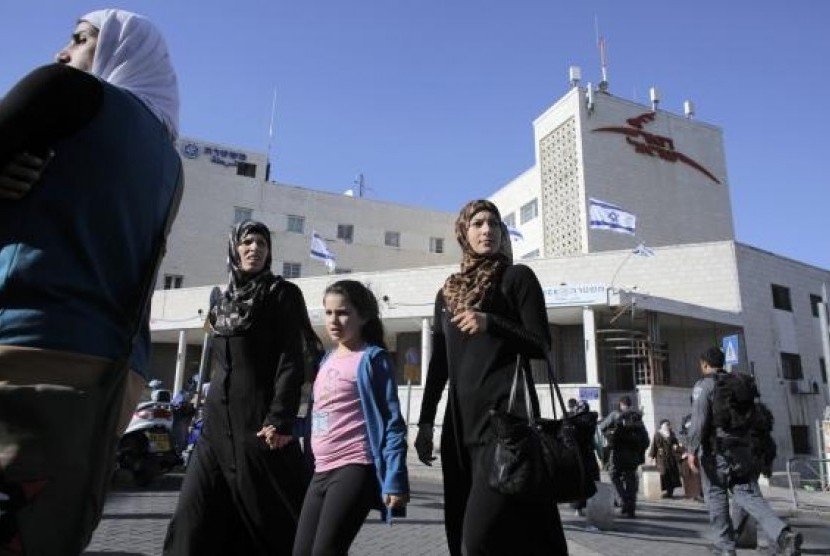 Palestinians walk past a post office building in East Jerusalem April 29, 2014. 