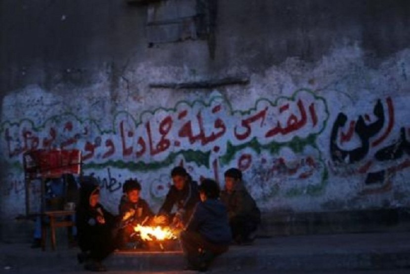 Palestinians warm themselves during a rainy day at Shati refugee camp in Gaza City March 14, 2014. 