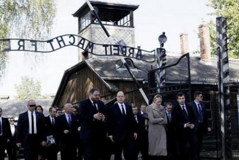 Pangeran Albert dari Monaco dan Putri Charlene melintasi pintu gerbang Arbeit Macht Frei bekas kamp Auschwitz di Polandia pada 19 Oktober 2012. Mantan tahanan tertua kamp konsentrasi tersebut meninggal, Ahad (21/10/2012) pada usia 108 tahun,.