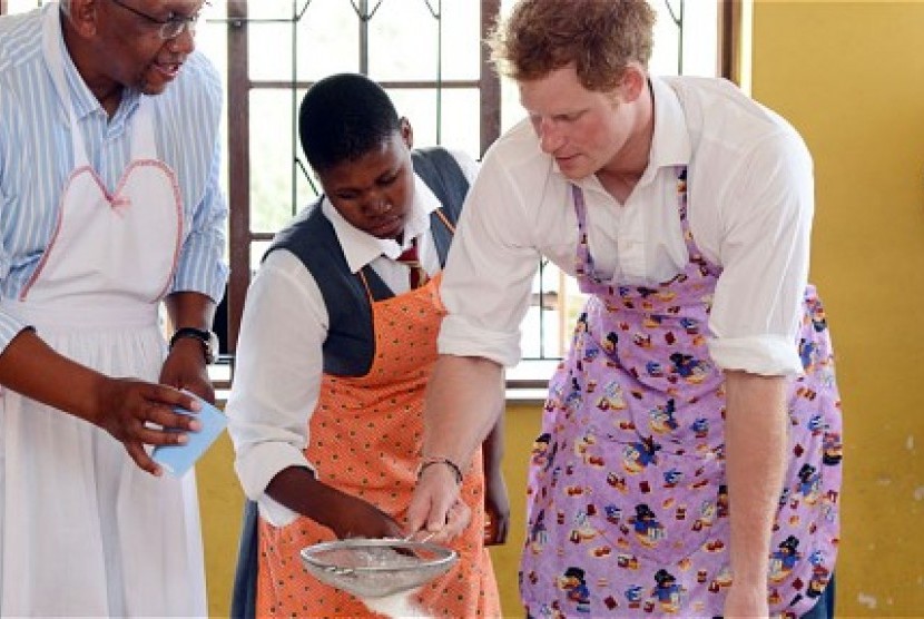 Pangeran Harry mengayak tepung untuk membuat, mokonye, donat khas Lesotho.