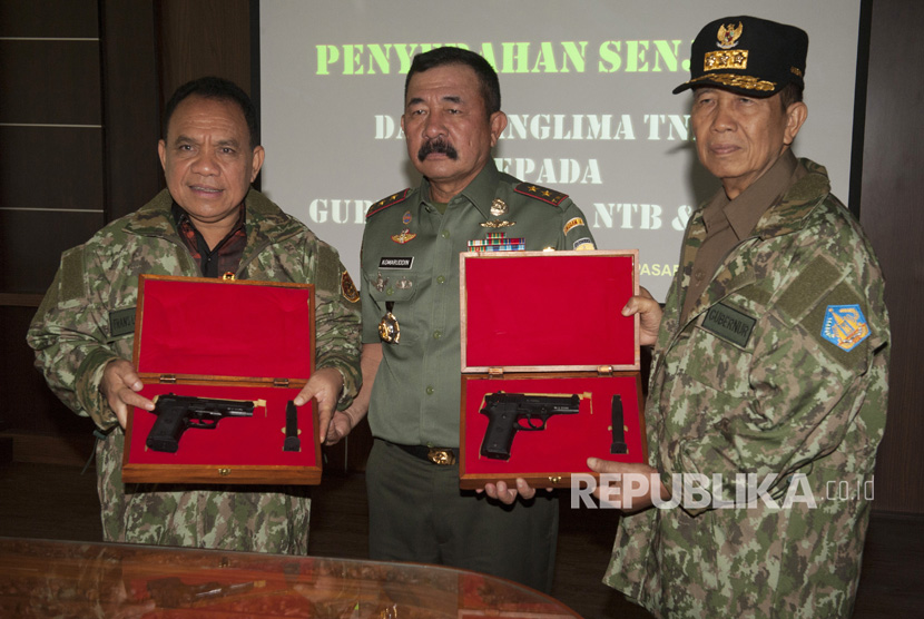 Panglima Kodam IX Udayana Mayor Jenderal TNI Komaruddin Simanjuntak (tengah) bersama Gubernur Bali Made Mangku Pastika (kanan) dan Gubernur NTT Frans Lebu Raya (kiri) memperlihatkan senjata api saat penyerahan senjata itu di Denpasar, Bali, Kamis (10/8). 
