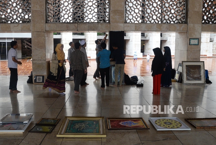 Panitia memasang kaligrafi untuk mempersiapkan pameran di Masjid Istiqlal, Jakarta, Ahad (19/2).