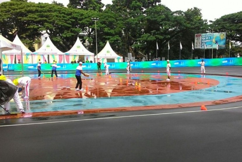 Panitia pelaksana berusaha mengeringkan lintasan sepatu roda di Saparua Sport Park, Bandung yang diguyur hujan menjelang final Individual Time Trial sepatu roda PON XIX, Kamis (22/9).