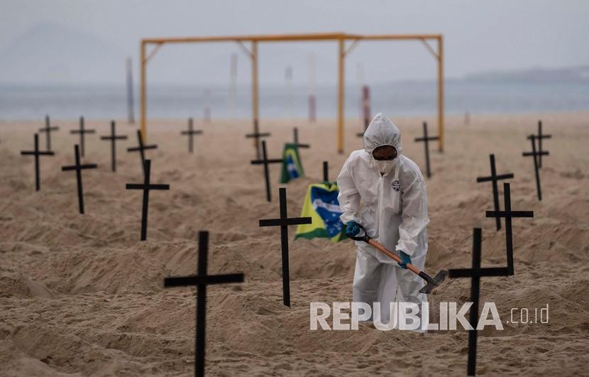  Para aktivis  dari LSM Rio de Paz dengan mengenakan kostum  menggali kuburan simbolis dalam memprotes penanganan pemerintah terhadap pandemi COVID-19 di pantai Copacabana, di Rio de Janeiro, Brasil, Kamis (11/6).