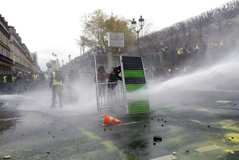  Para demonstran menggunakan jalanan untuk melindungi diri melawan water cannon aparat selama demonstrasi, Sabtu (1/12)