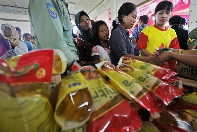 Para ibu tampak antre saat membeli minyak goreng kemasan di sebuah bazar.