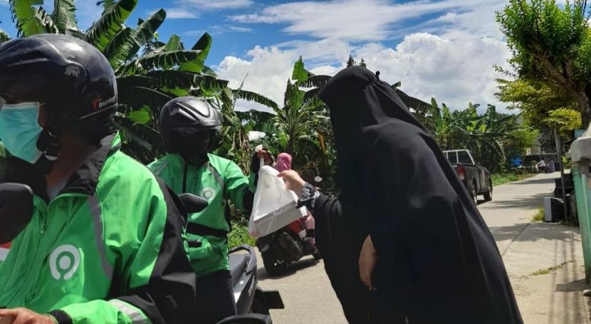 Para ibu yang tergabung dalam Kismis bekerja sama dengan BMH membagikan nasi kotak kepada para pekerja yang melintas di Jalan Kelurahan Pondok Rajeg, Cibinong, Bogor, Jumat (24/12).
