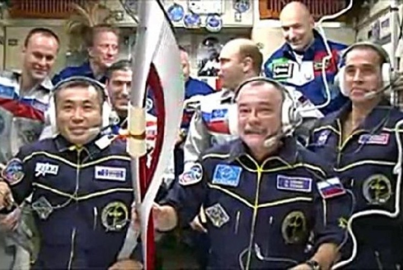Para kosmonot sedang bersiap-siap mengeluarkan Obor Olimpiade ke luar angkasa 