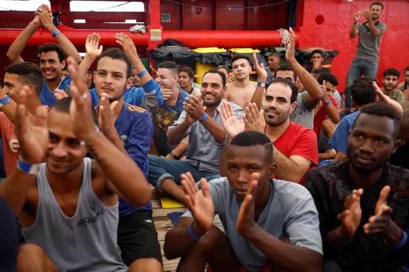 Para migran yang sebagian besar pria Mesir bertepuk tangan usai diberitahu diizinkan turun di Pelabuhan Messina, Sisilia, Italia, 26 Agustus 2022. Mereka telah berada di kapal penyelamat Open Arms Uno selama 10 hari di laut. Migran Mesir Diizinkan Berlabuh di Italia Usai Tertahan 10 Hari di Laut
