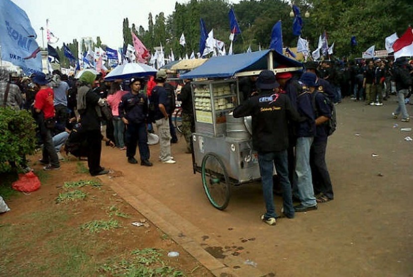 Para pedagang kaki lima (PKL) mendulang rizki dari para buruh yang menggelar demo di Jakarta, Kamis (12/7).