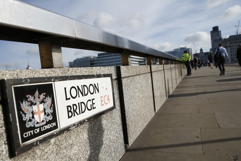 Para pejalan kaki melewati seorang polisi di London Bridge, London, Senin (5/6). Polisi menahan beberapa orang dan melakukan penyelidikan setelah rangkaian serangan diduga sebagai aksi terorisme menewaskan beberapa orang dan melukai lebih dari 40 lainnya di jantung kota London. 