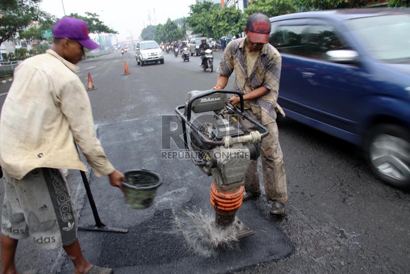 Para pekerja dari Dinas PU DKI Jakarta menambal jalan yang berlubang di Jalan Kramat Raya, Jakarta, Senin (17/6).    (Republika/ Yasin Habibi)