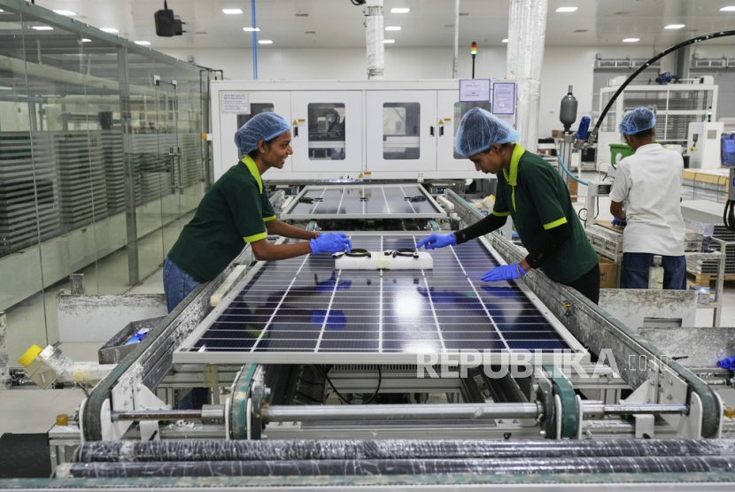 Para pekerja memasang sakelar dan konektor setelah keluar dari rangka otomatis di pabrik panel surya ReNew di pinggiran Jaipur, India, Kamis, 21 Agustus 2025.