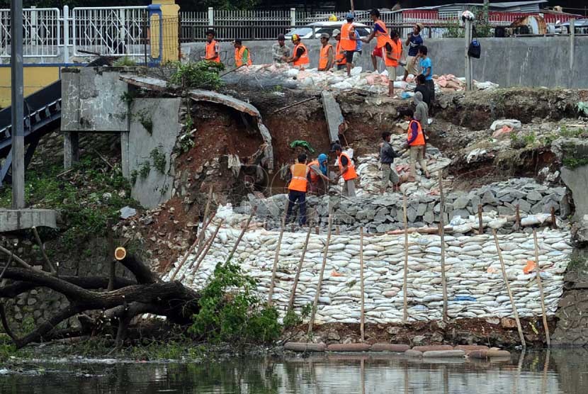Para pekerja menata batu kali saat memperbaiki tanggul waduk Setia Budi, Jakarta Pusat, Ahad (26/1). (