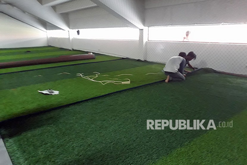 Para pekerja sedang menyelesaikan renovasi stadion Gelora Sriwijaya di komplek Jakabaring Sport City (JSC), diantaranya dengan pemasangan rumput sintetis tempat pemanasan di depan ruang ganti  yang akan digunakan untuk cabang sepakbola Asian Games XVIII-2018. 