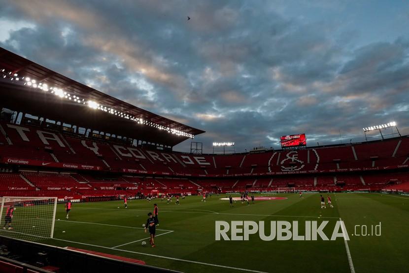 Para pemain Sevilla dan Betis melakukan pemanasan sebelum dimulainya pertandingan sepak bola La Liga Spanyol di Seville, Spanyol, Kamis (11/6). Liga Spanyol kembali dimulai lagi pada pekan ini setelah lebih dari tiga bulan ditangguhkan karena pandemi corona. 