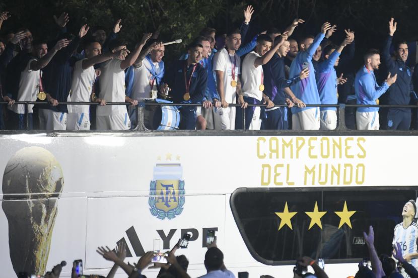 Para pemain tim sepak bola Argentina melambaikan tangan dari bus yang membawa mereka ke Asosiasi Sepak Bola Argentina, tempat mereka akan bermalam setelah mendarat di bandara Ezeiza di pinggiran Buenos Aires, Argentina, Selasa, 20 Desember 2022. 