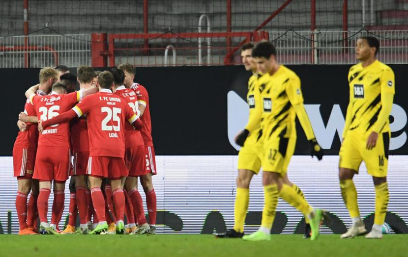 Para pemain Union Berlin (kostum merah) merayakan gol ke gawang Borussia Dortmund dalam pertandingan Bundesliga, Sabtu (19/12) dini hari WIB. Para pemain Dortmund hanya bisa tertunduk kecewa.