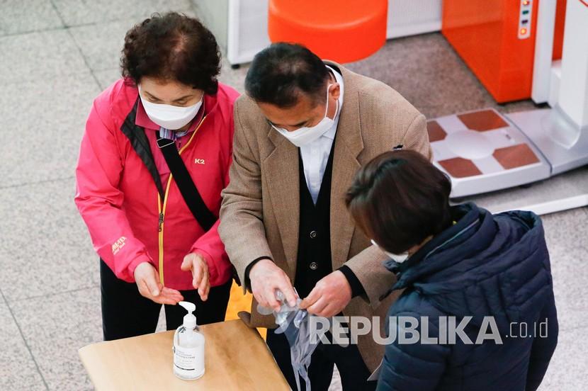 Para pemilih diberikan sarung tangan plastik untuk mencegah penularan Virus sebelum memberikan suara mereka di tempat pemungutan suara di Seoul, Korea Selatan, Rabu (15/4). Korea Selatan menyelenggarakan pemilihan umum di tengah kontrol ketat akibat berlangsungnya pandemi Covid-19. 