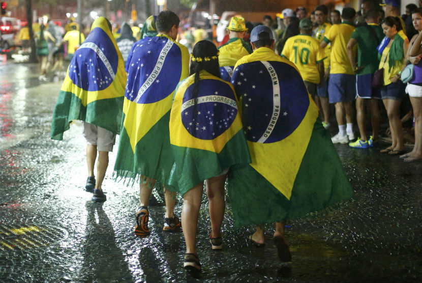 Para pendukung Brasil berjalan tanpa mempedulikan guyuran hujan usai menyaksikan Timnas Brasil menelan kekalahan menyakitkan dari Jerman di semifinal Piala Dunia 2014 di Rio de Janeiro pada Selasa (8/7). 