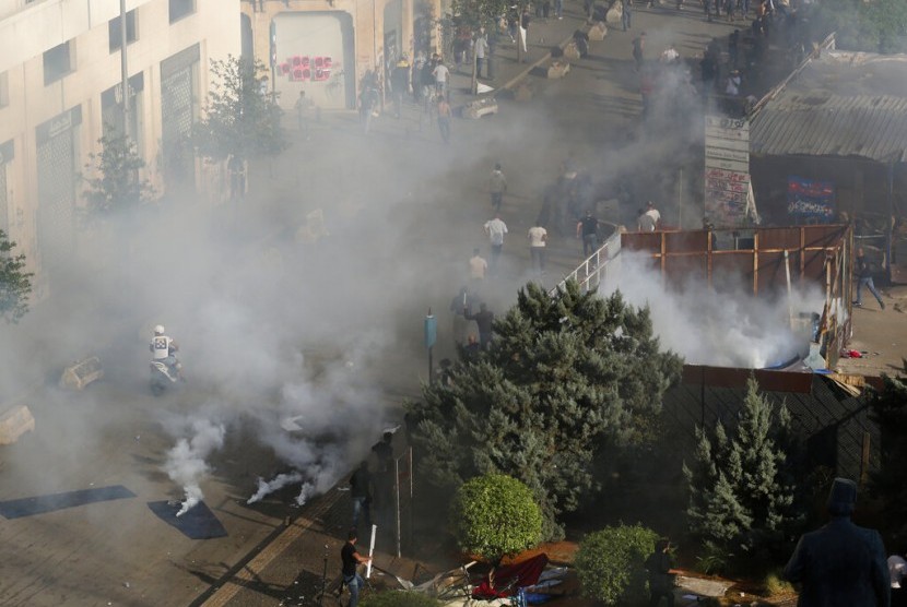 Para pendukung Hizbullah berlari usai polisi menembakkan gas air mata di dekat kantor pemerintahan di Beirut, Lebanon, Selasa (29/10).