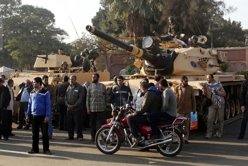 Para pendukung presiden Mursi berdiri dekat kendaraan lapis baja yang hanya dikerahkan di luar istana presiden Mesir di Kairo,Kamis (6/12). (Reuters/Asmaa Waguih)