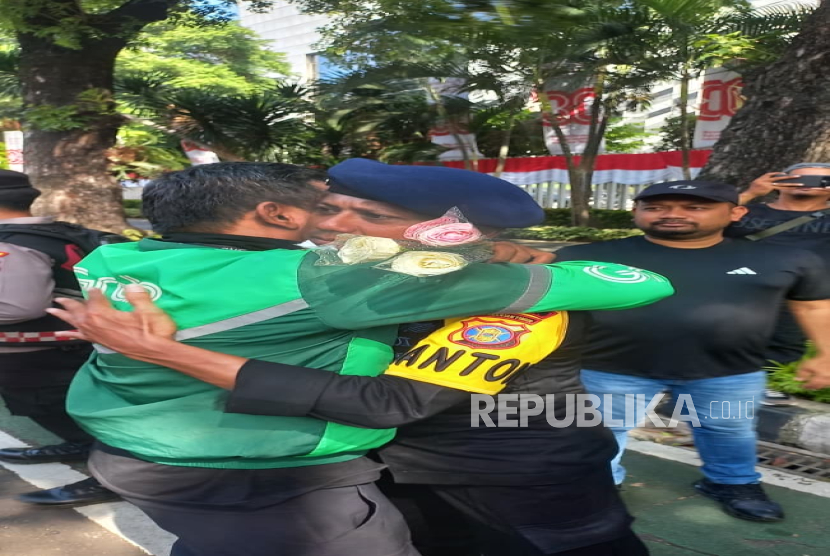 Para pengemudi ojek online (ojol) menggelar aksi damai dan membagikan bunga kepada aparat kepolisian, TNI, masyarakat, hingga awak media di Jalan Medan Merdeka Selatan, Jakarta, Selasa (2/9/2025).  