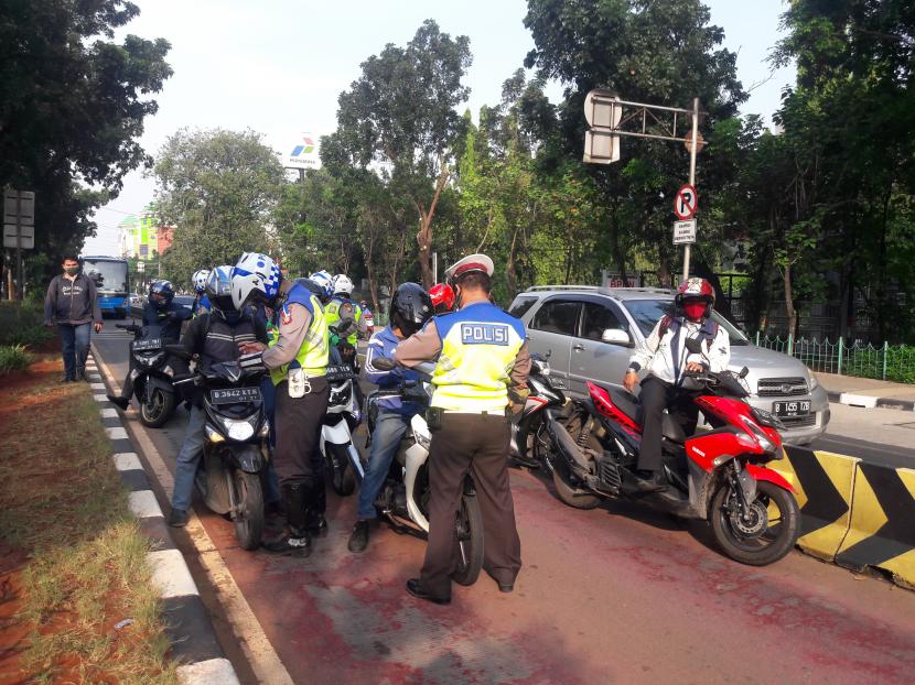 Petugas menilang sepeda motor yang masuk ke jalur bus Transjakarta di Jalan Sutoyo, Jakarta Timur.