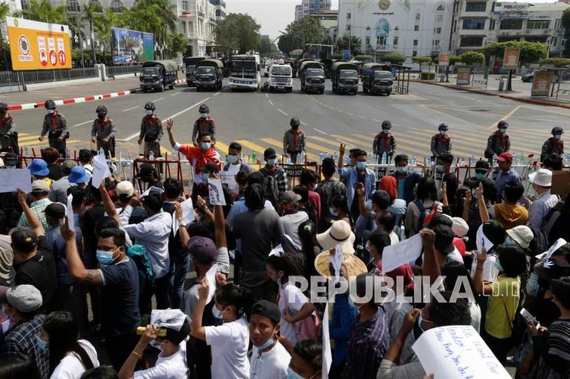 Para pengunjuk rasa berkumpul di depan barikade polisi yang memblokir jalan selama protes terhadap kudeta militer, di Yangon, Myanmar, Senin (8/2).