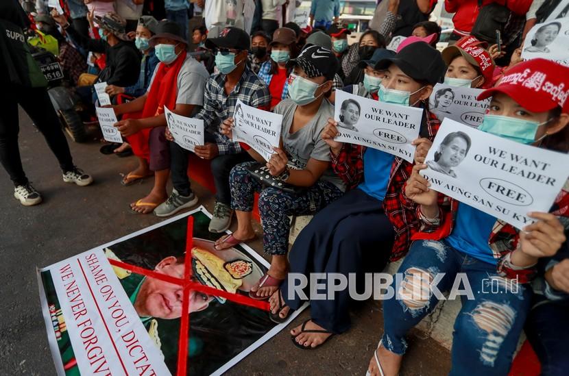  Para pengunjuk rasa memamerkan foto-foto pemimpin nasional Aung San Suu Kyi, dan meletakkan kaki mereka di atas gambar Panglima Tertinggi militer Myanmar Jenderal Min Aung Hlaing selama protes terhadap kudeta militer di Yangon, Myanmar Kamis (11/2). Kerumunan besar yang berdemonstrasi menentang pengambilalihan militer di Myanmar kembali menentang larangan protes.