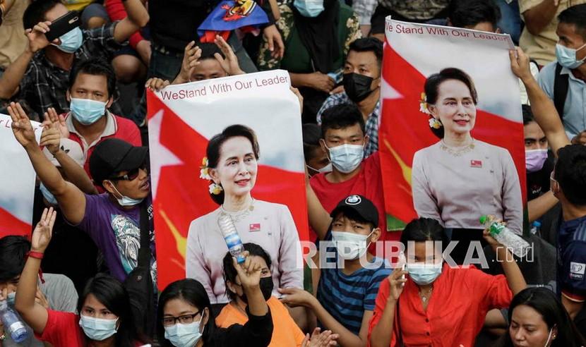 Para pengunjuk rasa memberi hormat tiga jari, simbol perlawanan, saat mereka memasang spanduk yang menggambarkan pemimpin Aung San Suu Kyi selama protes terhadap kudeta militer, di Yangon, Myanmar, Sabtu (6/2). Ribuan orang mengambil bagian dalam protes di Yangon .