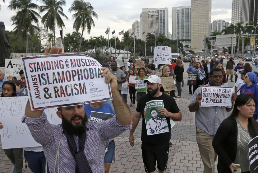 Para pengunjuk rasa meneriakkan slogan menentang perintah kebijakan pemrintahan Presiden Donald Trump terhadap imigran Muslim, Kamis, (26/1), di pusat kota Miami.