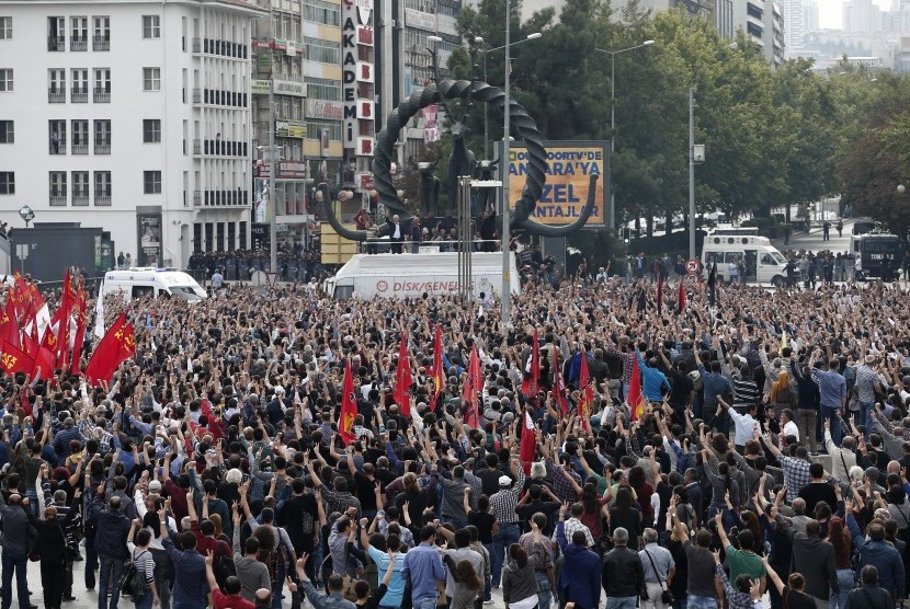 Para pengunjuk rasa mengangkat kepalnya sebagai bentuk penghormatan terhadap korban meninggal dalam pengeboman di Ankara, Turki, Ahad (11/10).