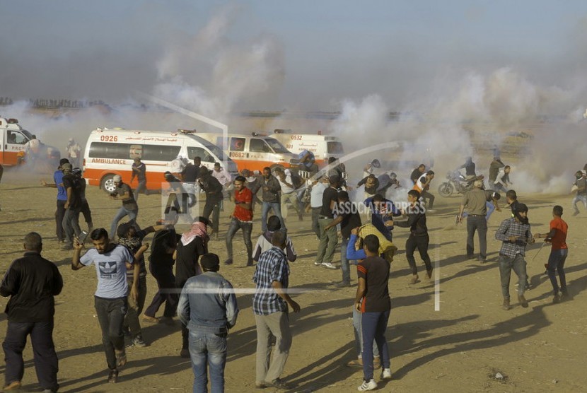  Para pengunjuk rasa Palestina berlindung dari gas air mata yang ditembakkan oleh pasukan Israel selama protes di perbatasan Jalur Gaza dengan Israel, sebelah timur Khan Younis, Jalur Gaza, pada Senin, 14 Mei 2018. Ribuan warga Palestina melakukan protes di dekat perbatasan Gaza dengan Israel saat Israel sedang mempersiapkan perayaan meriah Kedutaan Besar AS di Yerusalem.