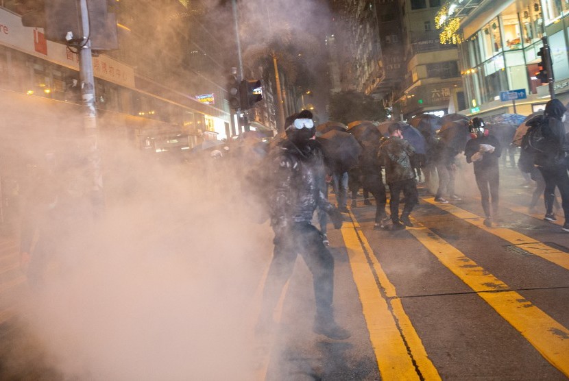 Para pengunjuk rasa pro-demokrasi bereaksi setelah polisi antihuru-hara menembakkan gas air mata selama demonstrasi di Tsim Sha Tsui, Hong Kong, China, Selasa (24/12), atau pada malam Natal 2019.