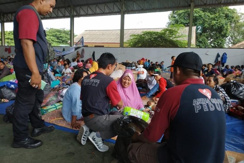 Para relawan Artha Graha Peduli (AGP) memberikan bantuan berupa keperluan bayi kepada seorang ibu di lapangan tenis Kalianda yang merupakan lokasi pengungsian untuk warga Pulau Sebesi dan Pulau Sebuku, Lampung Selatan, Kamis (27/12).