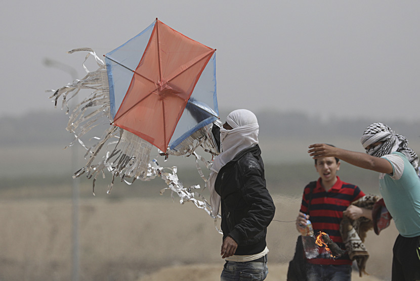 Para remaja Gaza menaikkan layang-layang yang membawa bara api dan minyak untuk dijatuhkan di lahan-lahan Israel selama bentrokan di dekat perbatasan Israel di timur Kota Gaza. 