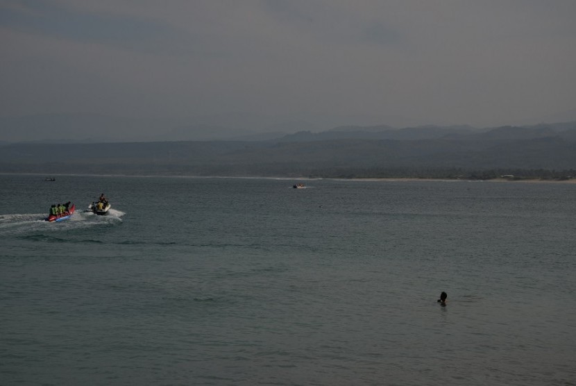 Para wisatawan bermain dan larut dalam keindahan pantai Cilautereun, Garut. 