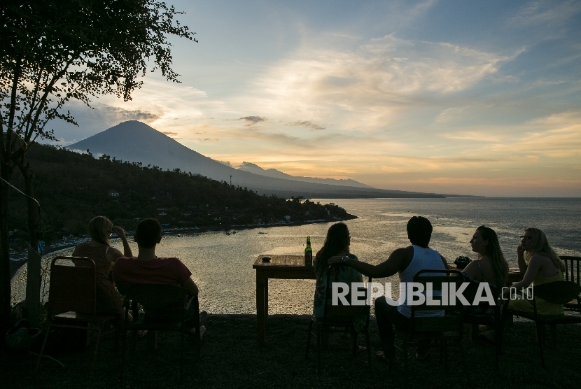 Para wisatawan menyaksikan matahari terbenam di atas Gunung Agung dari desa Amed di Karangasem, Bali, Indonesia (10/10).