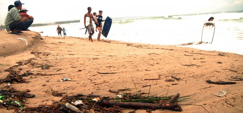 Para wisatawan sedang menikmati pantai Kuta yang dikotori banyak sampah, Ahad (29/1). (Republika/Rusdy Nurdiansyah)